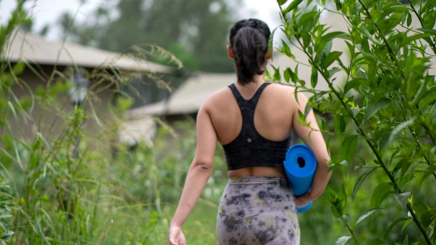 A person walking towards our tents near haridwar with a blue yoga mat in her hand - Aalia Jungle Resort & Spa