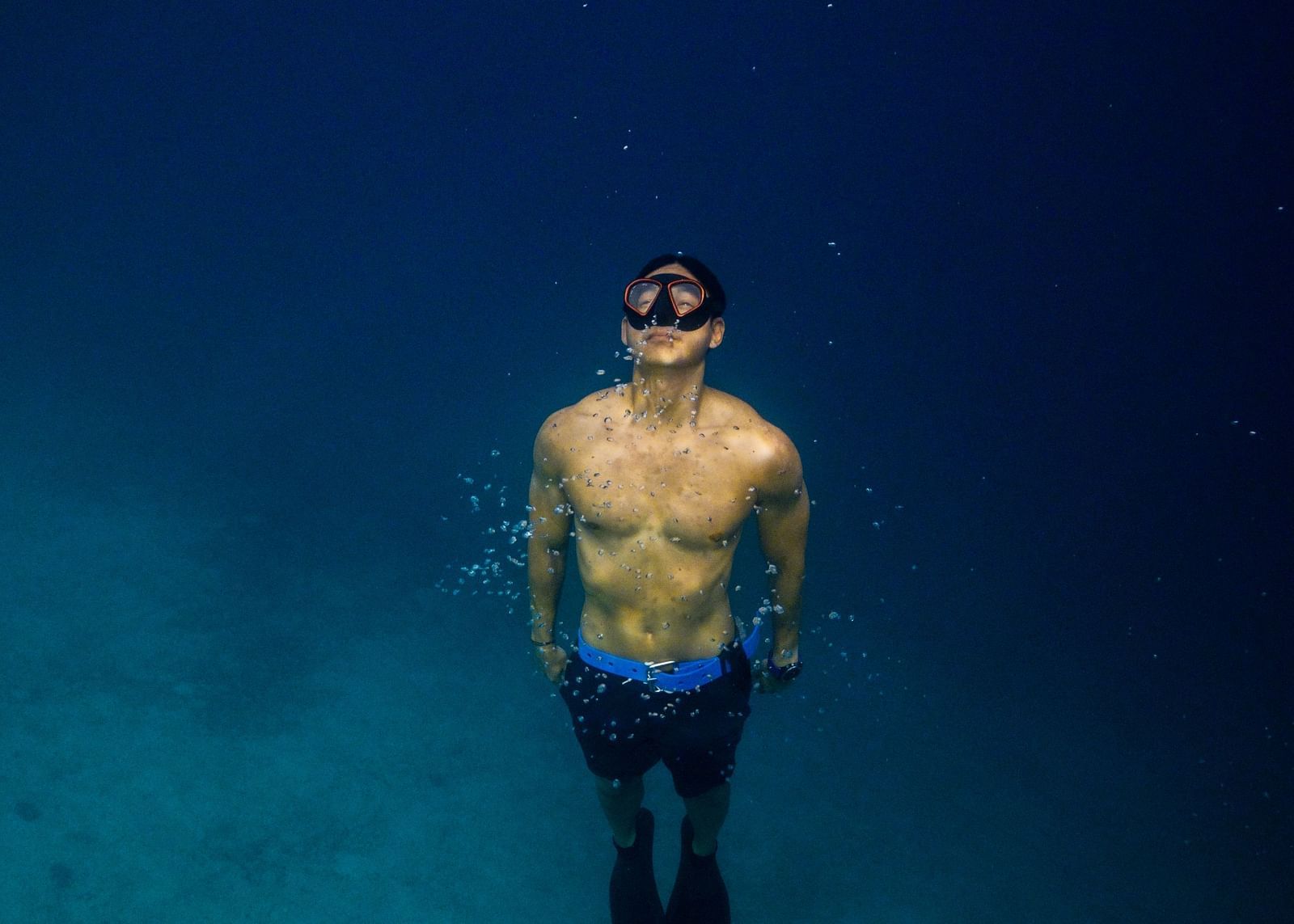 Person floating in deep blue sea, viewed from above, near Flower Island Resort.