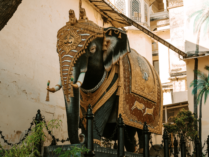 An elephant statue near a domed building in Udaipur.