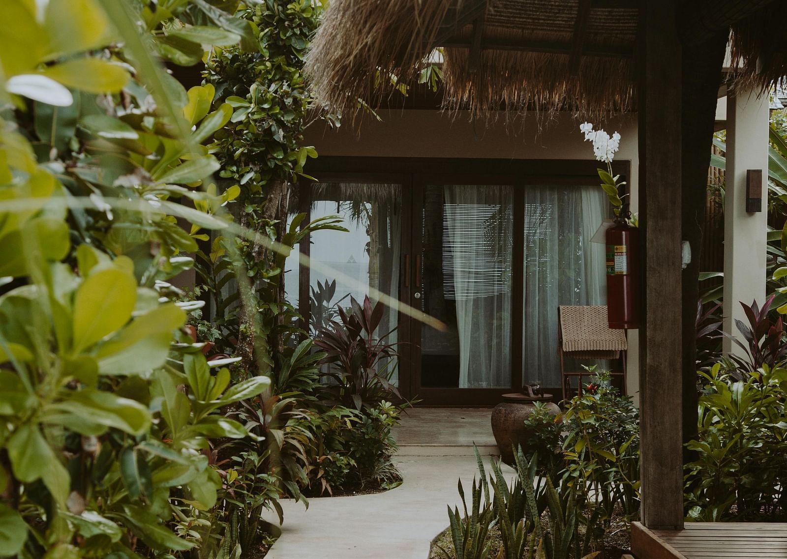 image of an entrance to a hotel with a walkway surrounded with lush greenery