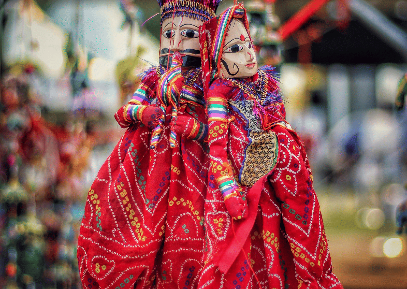 Close-up of brightly coloured, traditional Rajasthani puppets hanging from strings.