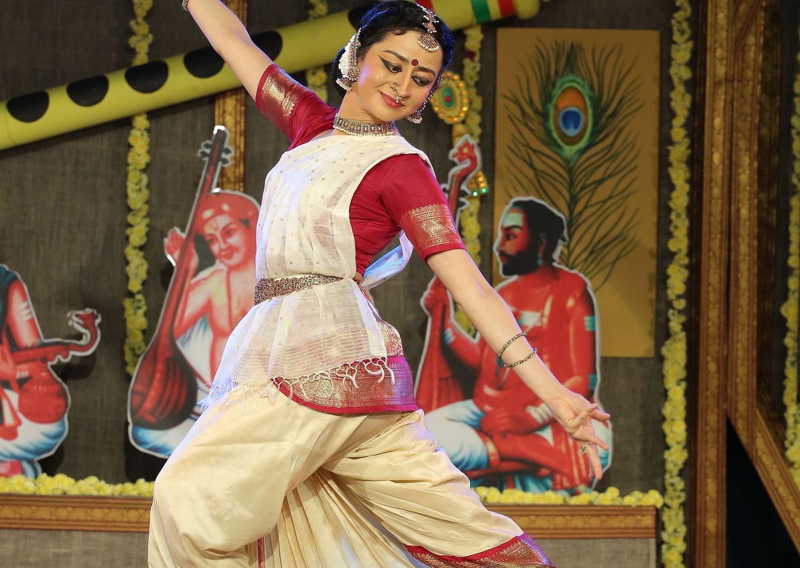A bharathanatyam dancer performing on stage wearing a white saree.