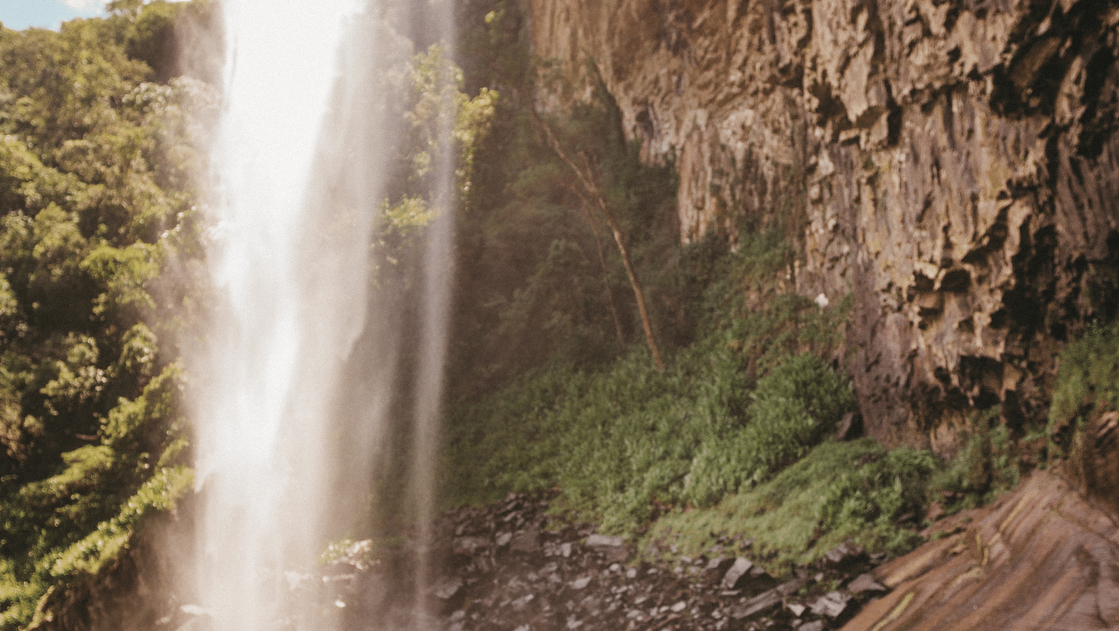 an image of a person watches the Kataldhar Waterfall with blue sky in the background