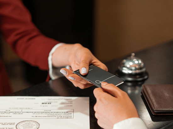 The receptionist handing over the key card to a guest over the front desk.