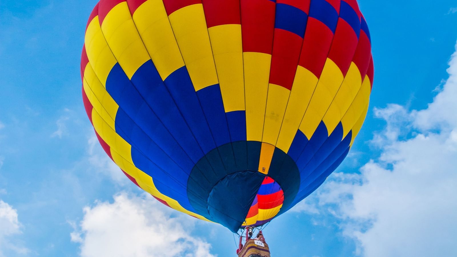 a colourful hot air balloon in the sky with white clouds and blue sky in the background
