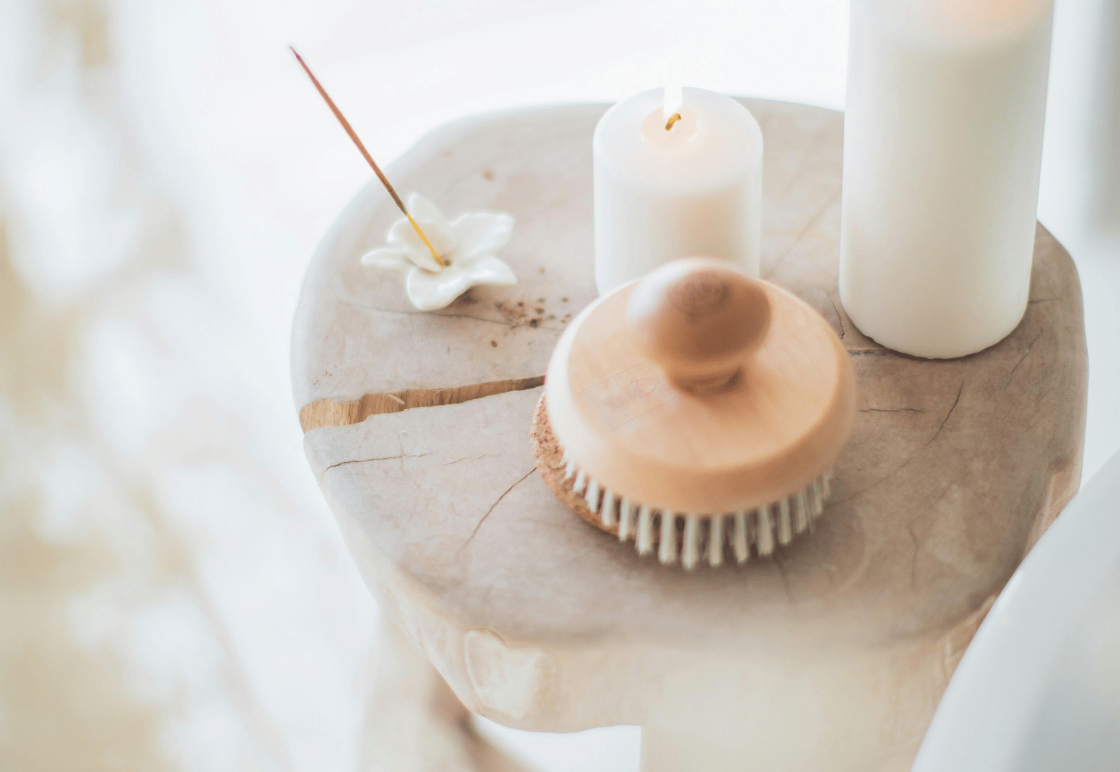 Spa setting with candles, towels, and a brush, immersed in a white background.