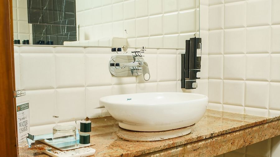A bathroom with a white sink set into a wooden vanity unit, with a mirror and shelves below, at Orsino Spa Resort.