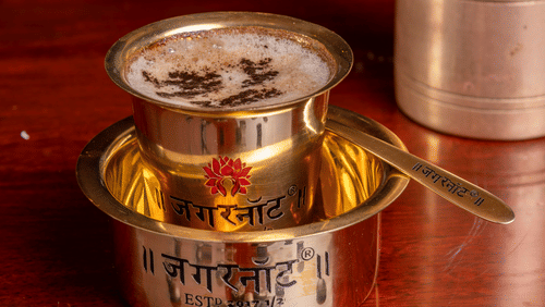 a close up shot of a South Indian Filter coffee serves in a steel cup