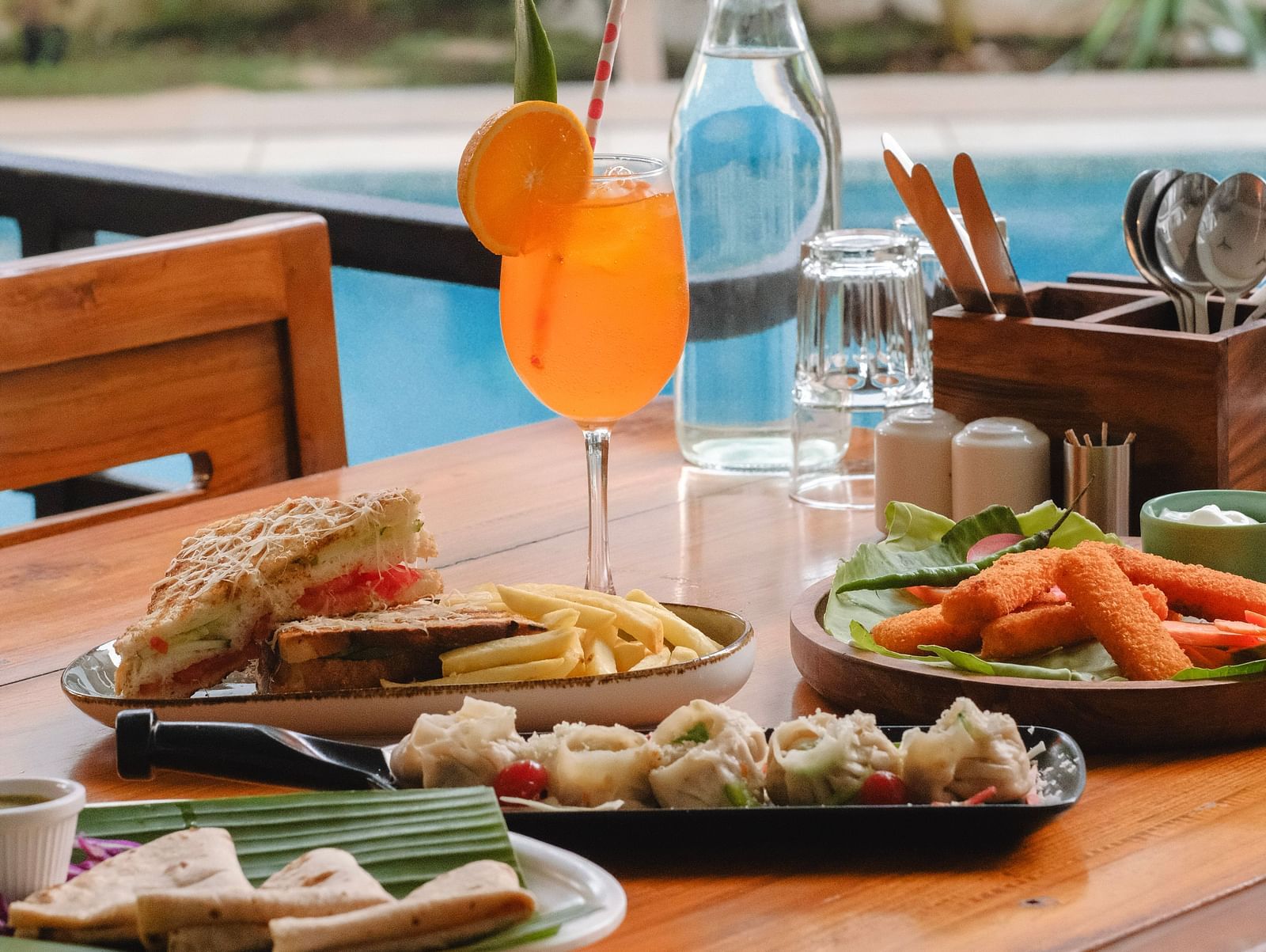 Refreshing orange drink and sandwiches served at a poolside dining table at The Verda de Miranda Resort.