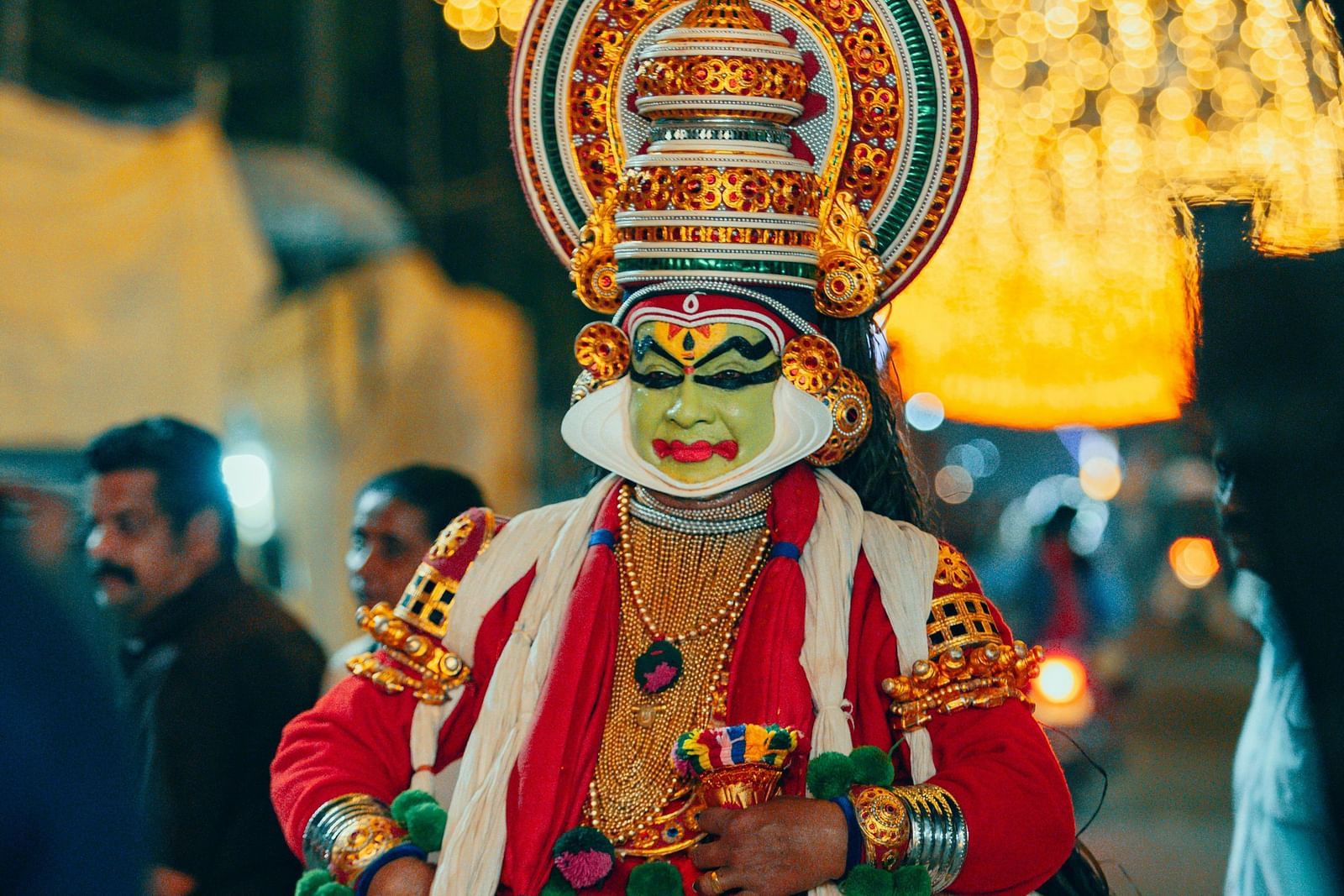 an image of a person performing kathakali with illuminating yellow lights in the background