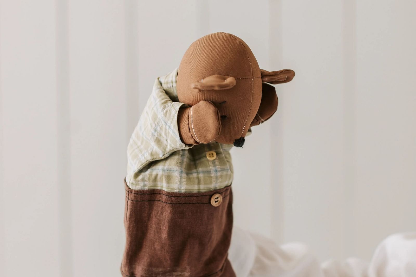 Bear toy with a hat, standing near a curtain, simple and cut.