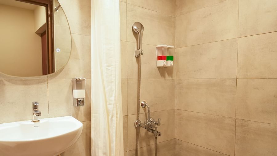 Image of bathroom featuring a mirror mounted over a sink and a space dedicated to shower next to it