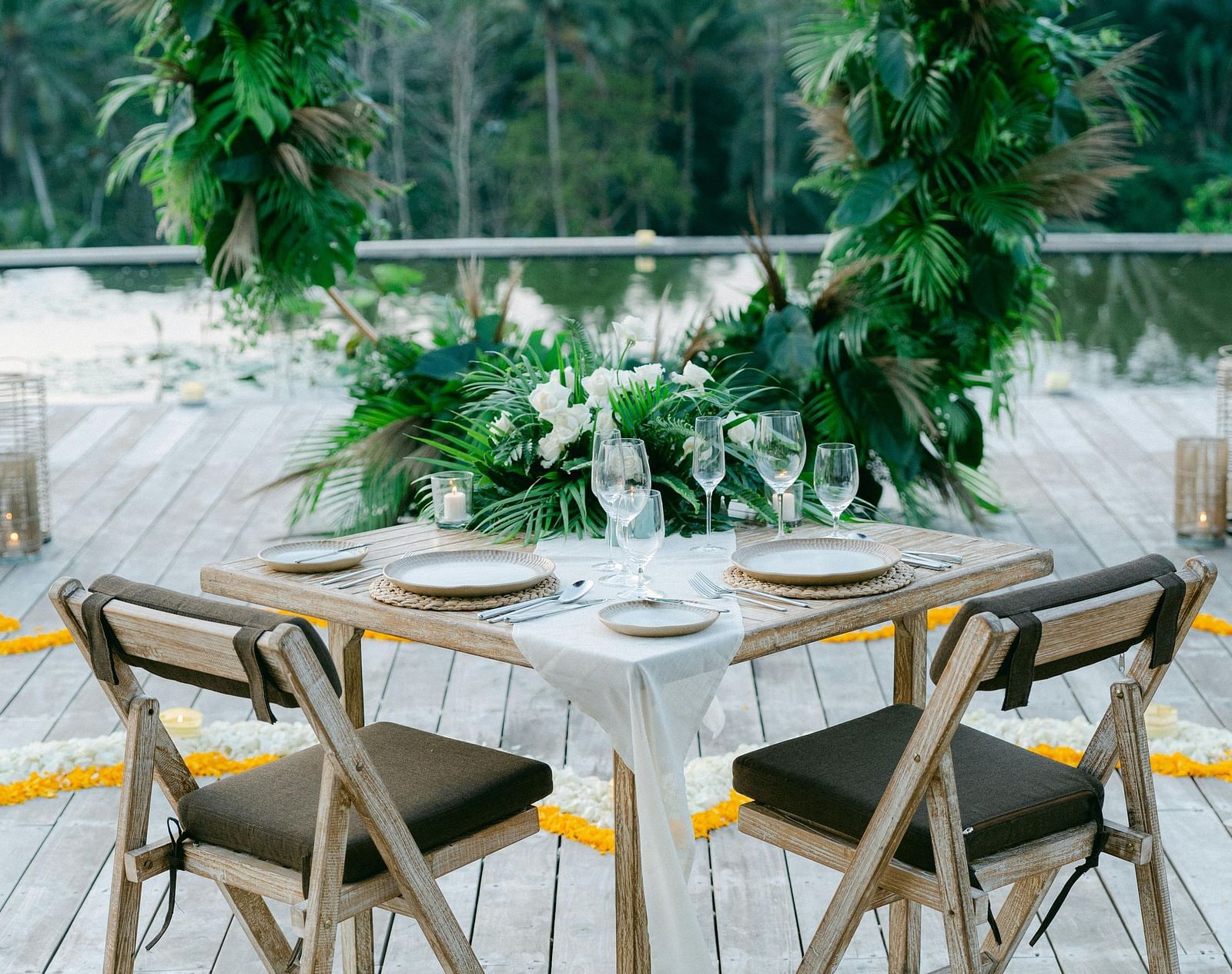 A balcony with a table and chairs overlooking lush trees.