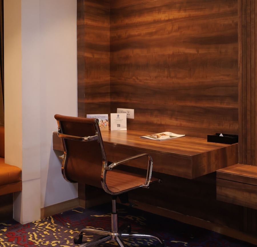 A work desk and a corner table with wooden finish on a carpetted floor at Best Western, Vrindavan 