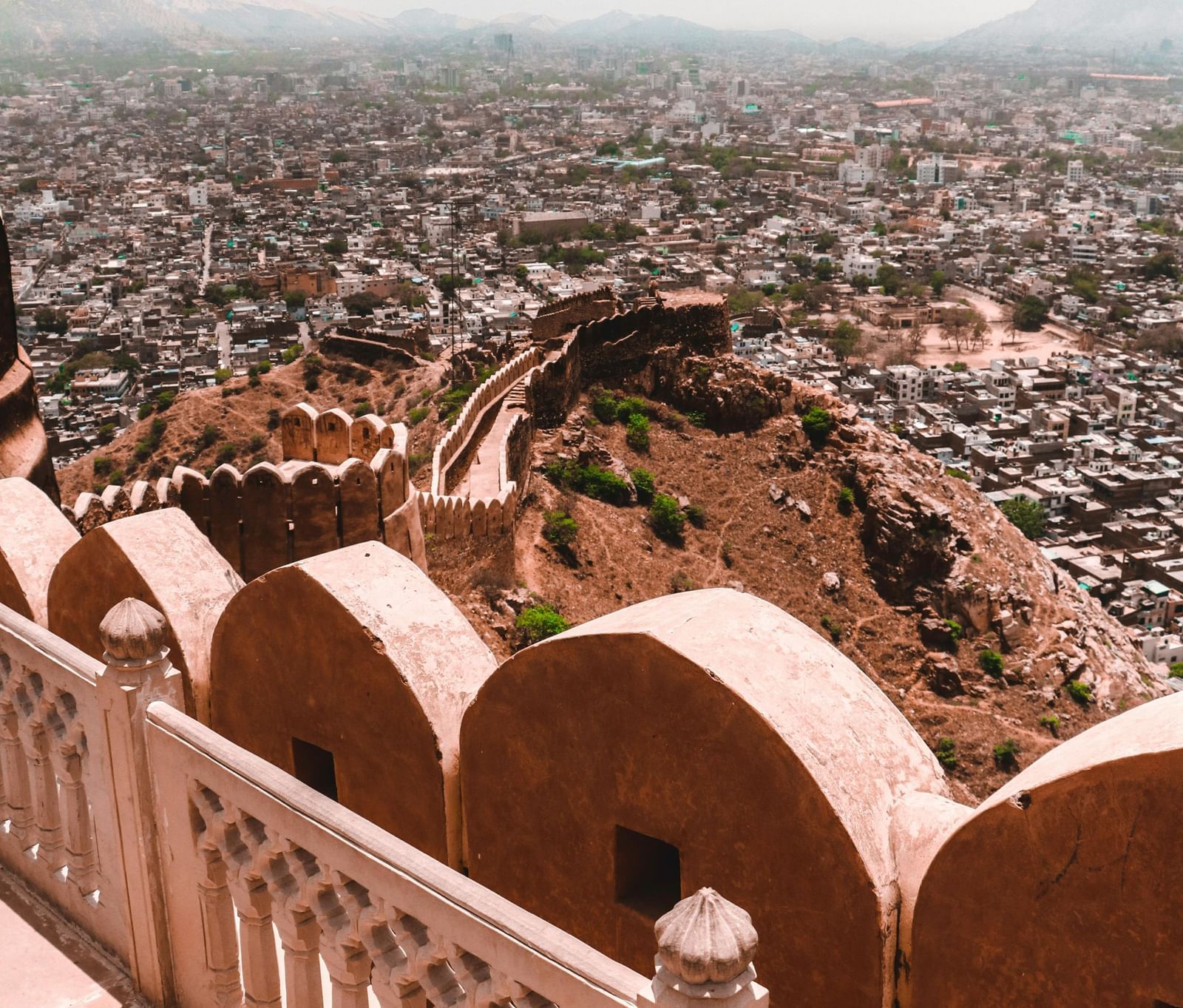 Panoramic view of a city taken from a fort, showing rooftops and distant hills.