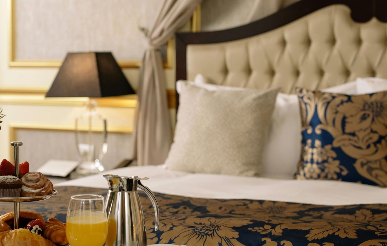 Elegant hotel room with a luxurious bed and breakfast served on a table.