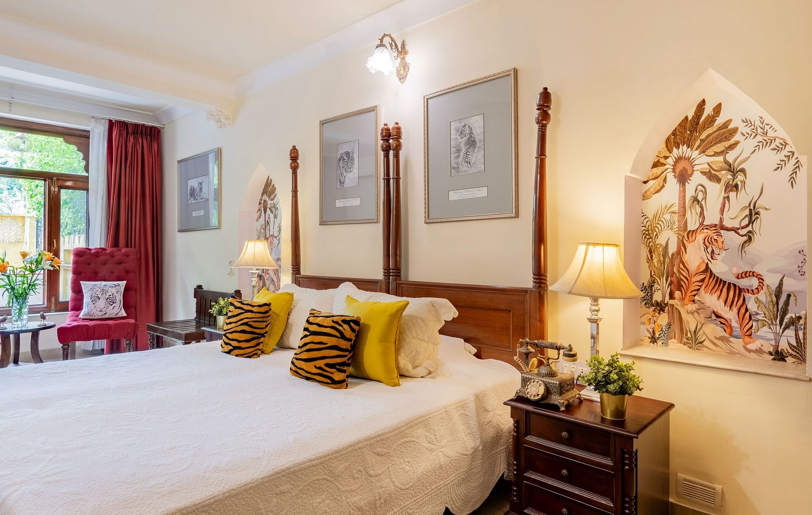 A bedroom with a four-poster bed, white linens, yellow cushions, a patterned rug, and a decorative niche in the wall | Dera Rawatsar, Jaipur