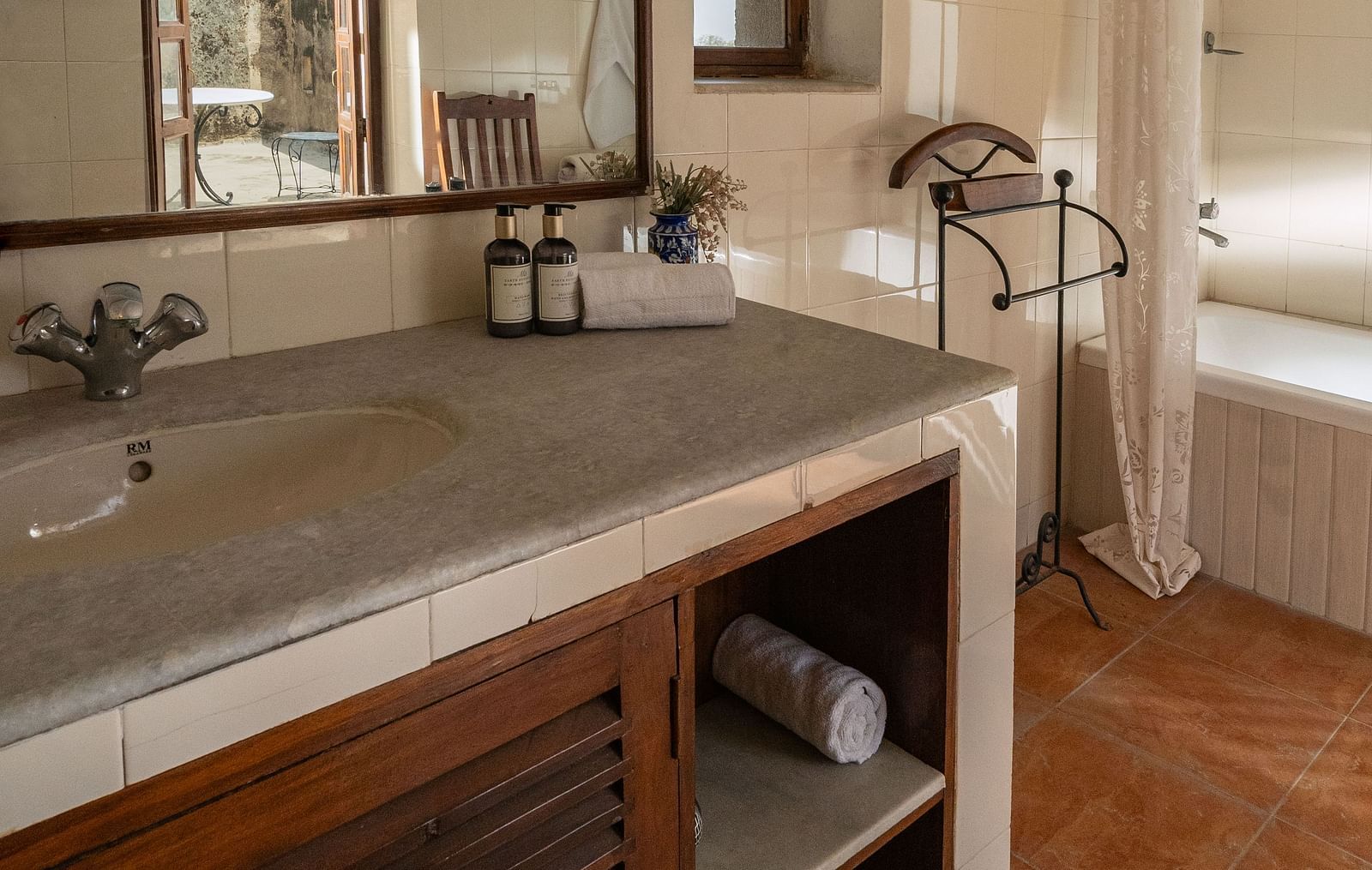 A bathroom at Fort Barli, Ajmer, features a sink, large mirror reflecting another room, and a bathing area.