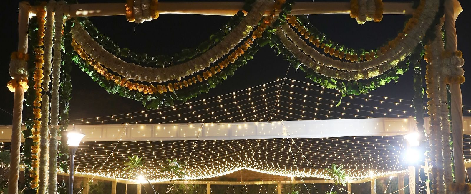 Entrance arch with gold drapes and floral decor on a red carpet at Tisya Farms, Gurgaon.