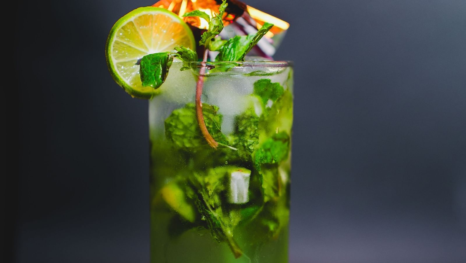 Refreshing green mojito garnished with lime, mint, and a tiny snack pack — a vibrant beverage creation from D Café at Dip Holidays.