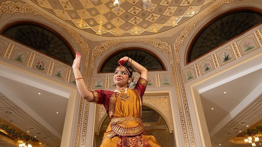 A Bharatanatyam dancer performs in a grand hotel lobby with a domed, gold-adorned ceiling and chandelier - Heritage Village Resorts & Spa, Manesar