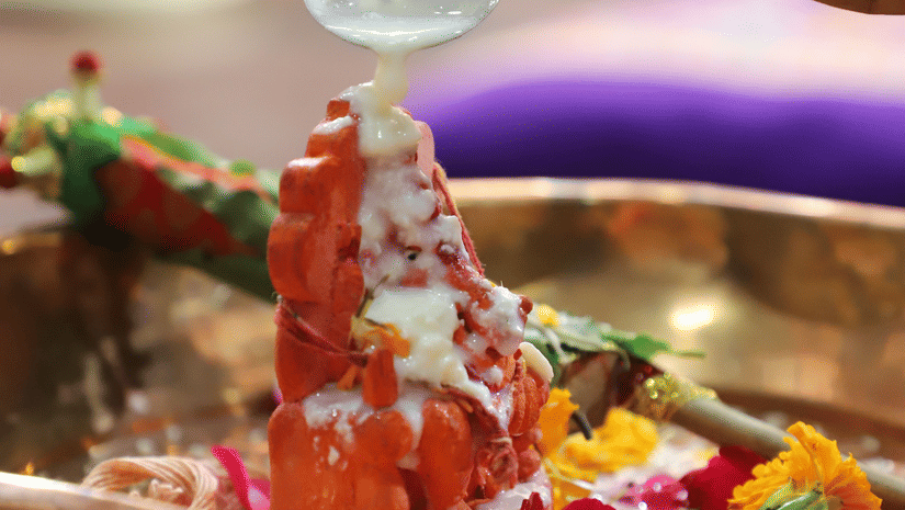 Devotees perform a traditional prayer ceremony with offerings before a beautifully decorated Ganesha idol.