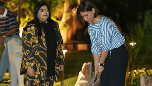 Women playing golf at night, with a dark sky and well-lit pathways