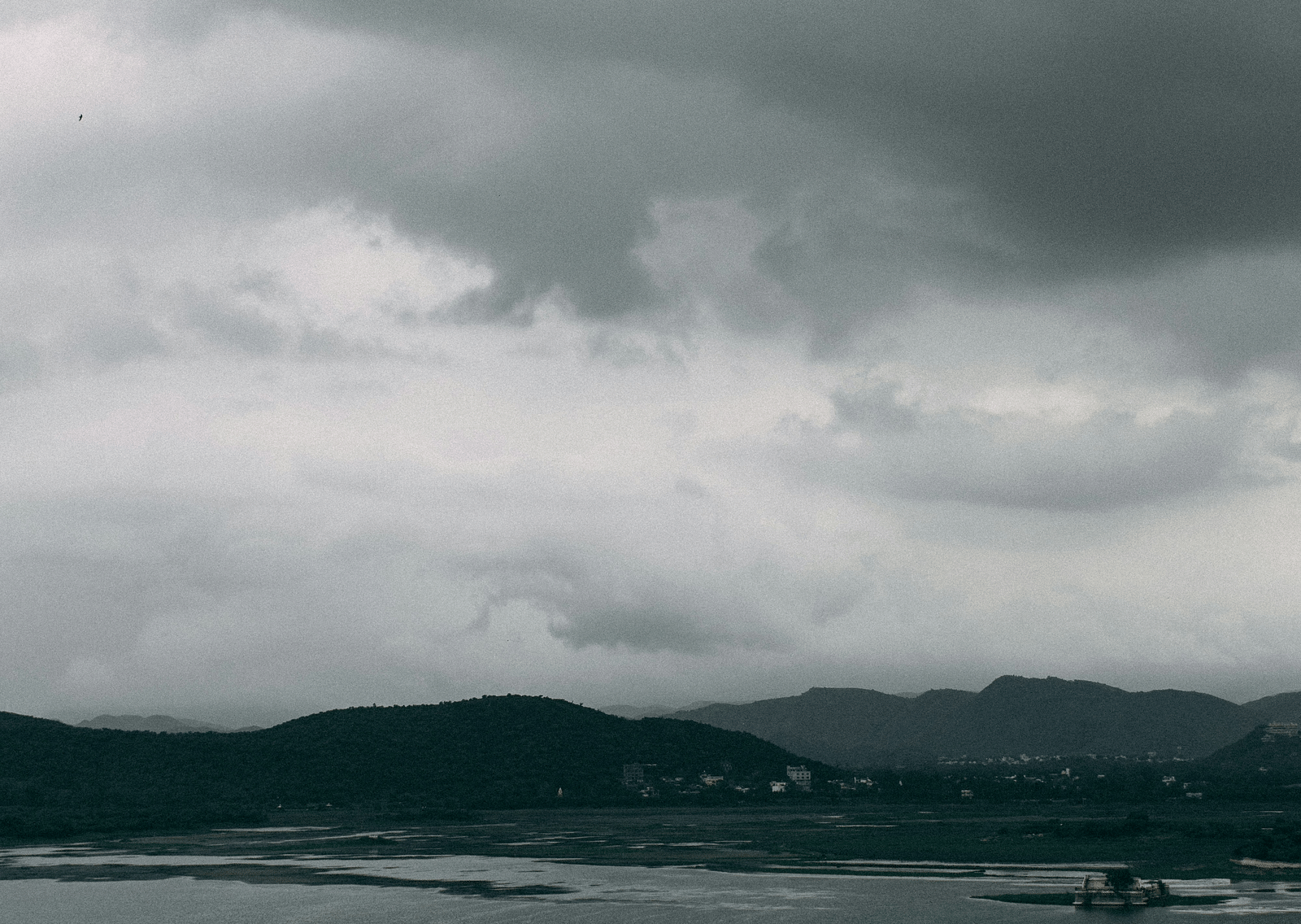 An overview of a building on a waterbody with dark clouds above it.