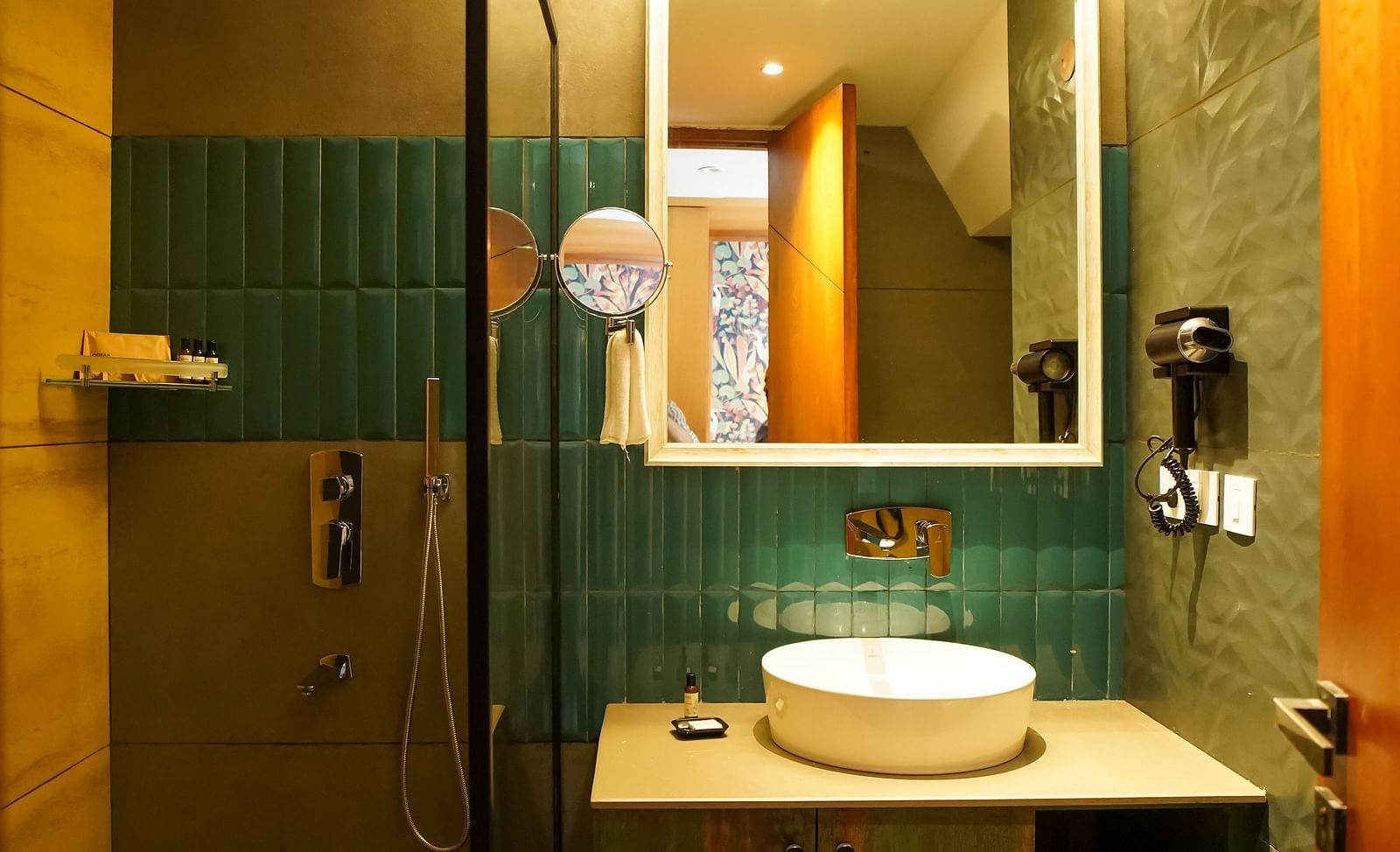 A bathroom with a modern sink vanity, a large mirror, and a toilet visible in the reflection | Deluxe Room | Sukama Resort & Spa, Nainital