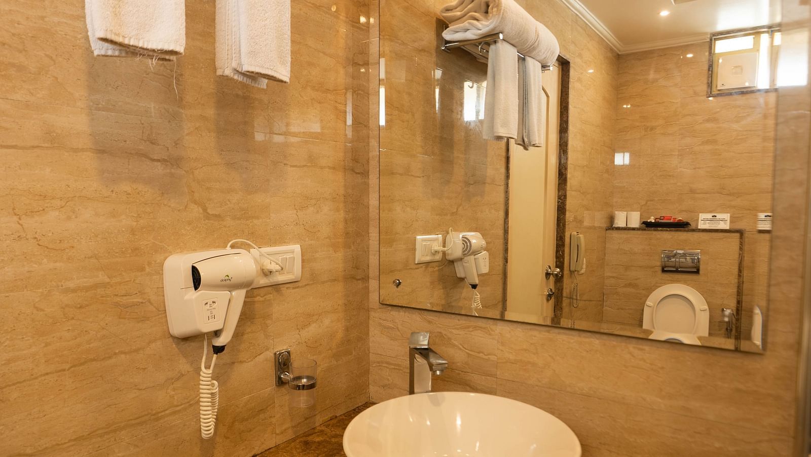 A restroom at Hotel Pai Viceroy Jayanagar featuring a wash basin, toiletries and a mirror