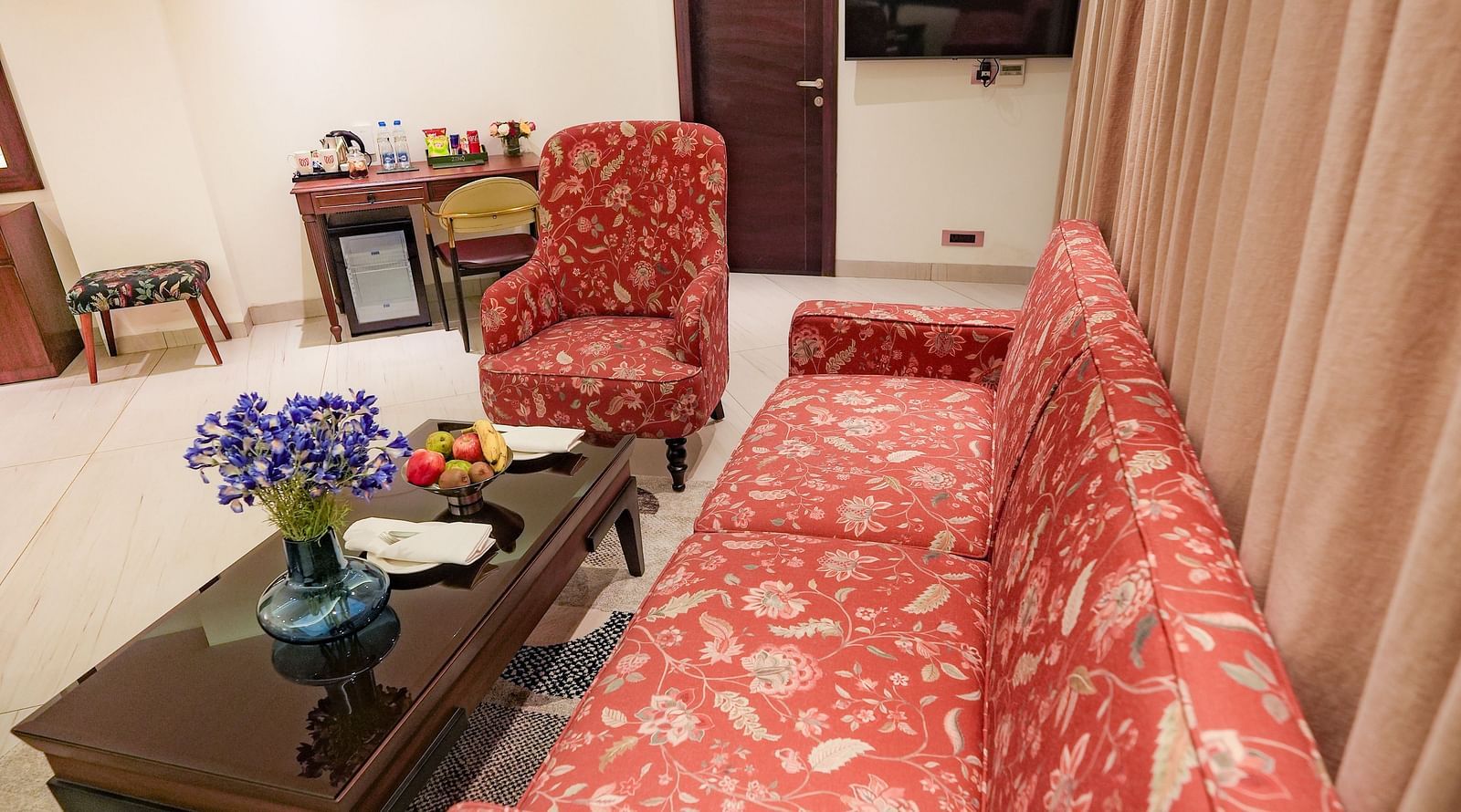 An image of a living area in our suite in Bankhandi with upholstered furniture placed around a teapoy with a flower vase - NAMAMI BY ZENQ BANKHANDI