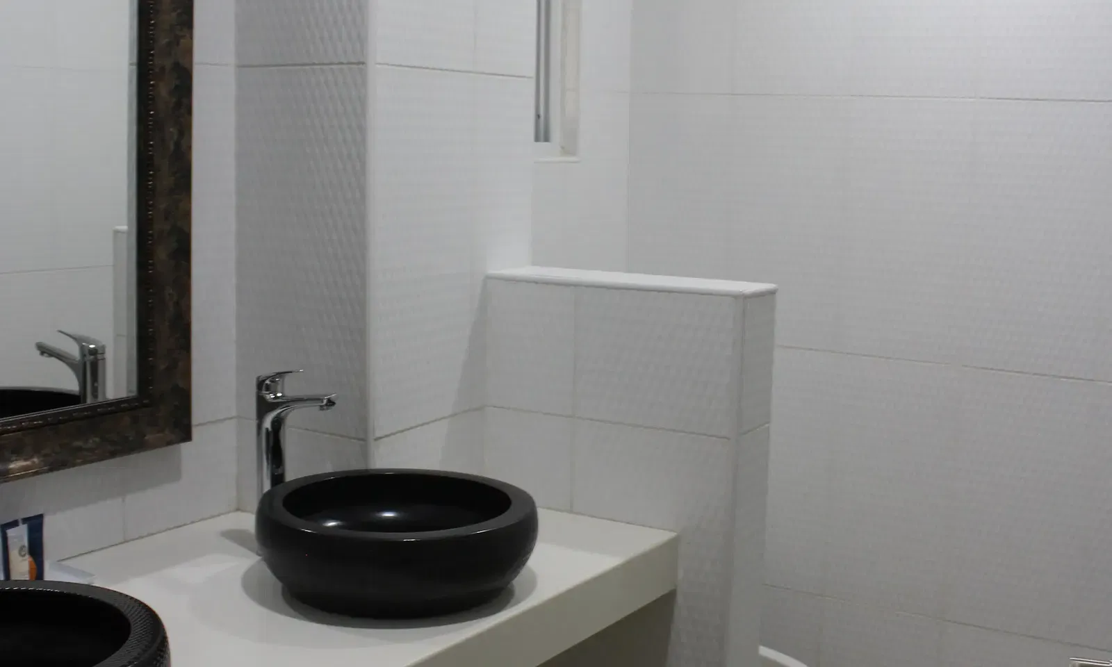 A minimalist bathroom shows a black circular sink on a white vanity with a large mirror above it | Executive King Room | Altamont Court, Jamaica