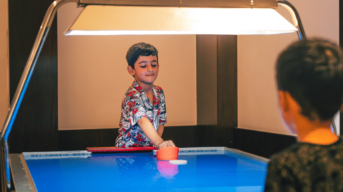 Two kids playing an indoor game on a blue table Image at The Ananta Udaipur