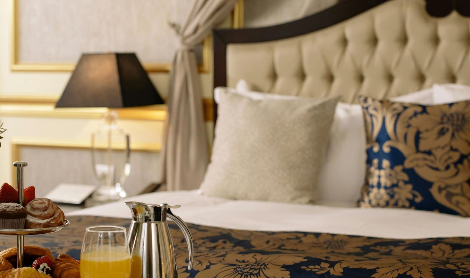 Elegant hotel room with a luxurious bed and breakfast served on a table.