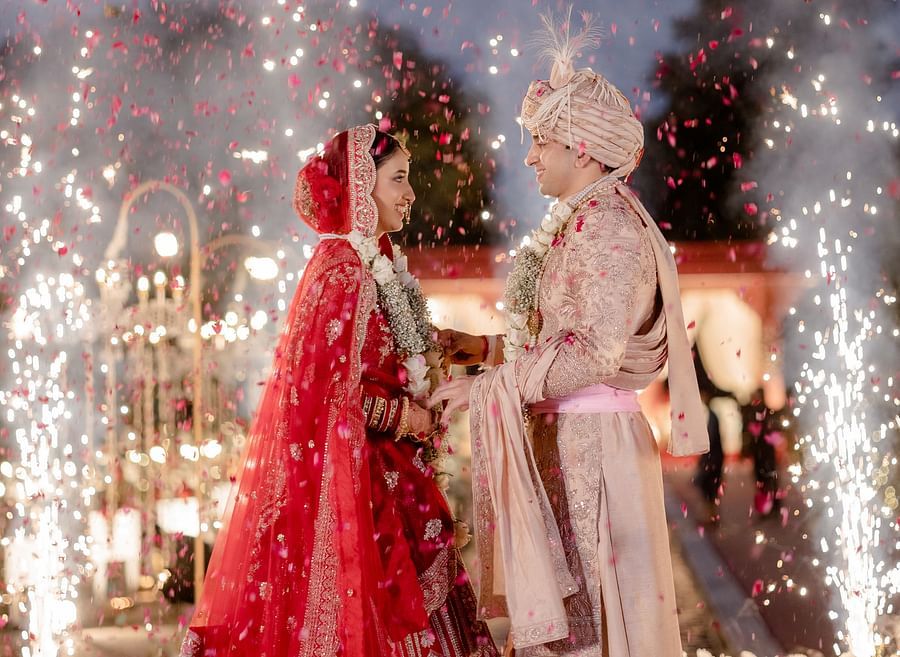 Couple celebrating amidst floral showers and fireworks after garland exchange at Umaid palace.