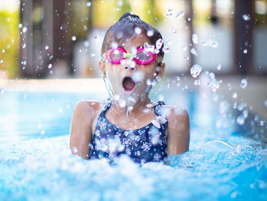 A child wearing swimming goggles looks awe-struck while enjoying the pool - best resort near Delhi with private pool