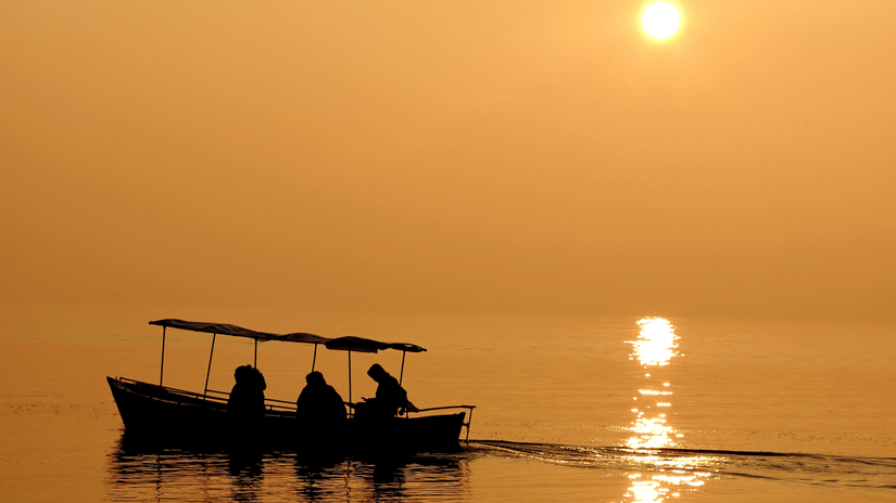 A group of people out on a boat ride during sunset.