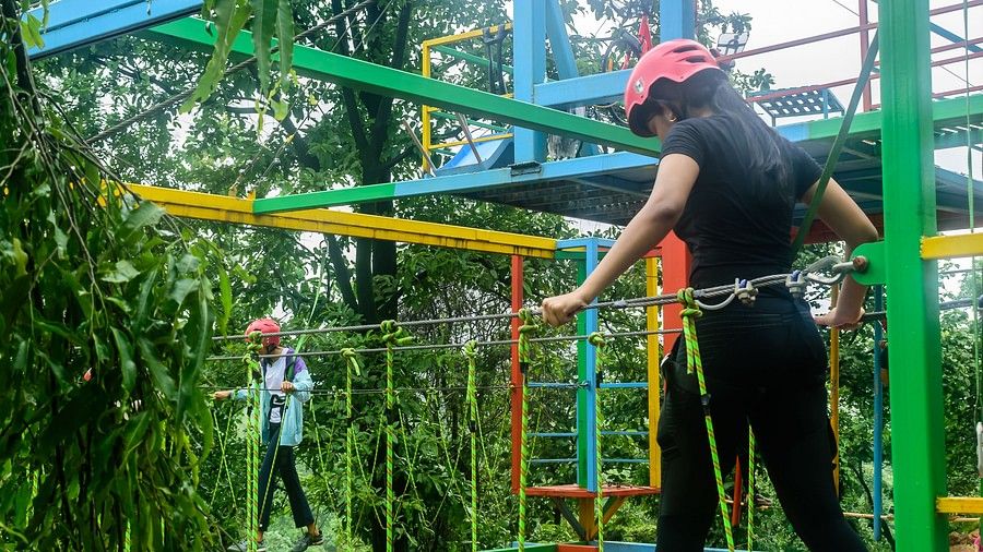 A portrait of a girl on a burma bridge with helmets and safety equipments making her way across the walkpath