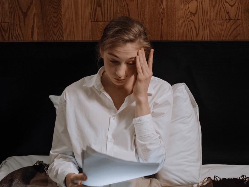 a person stressed out looking at stacks of papers and a laptop