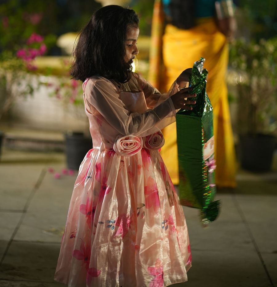 A little girl dressed in a pink dress opening a gift wrapped in green wrapping paper at Rangamati Garden Resort.
