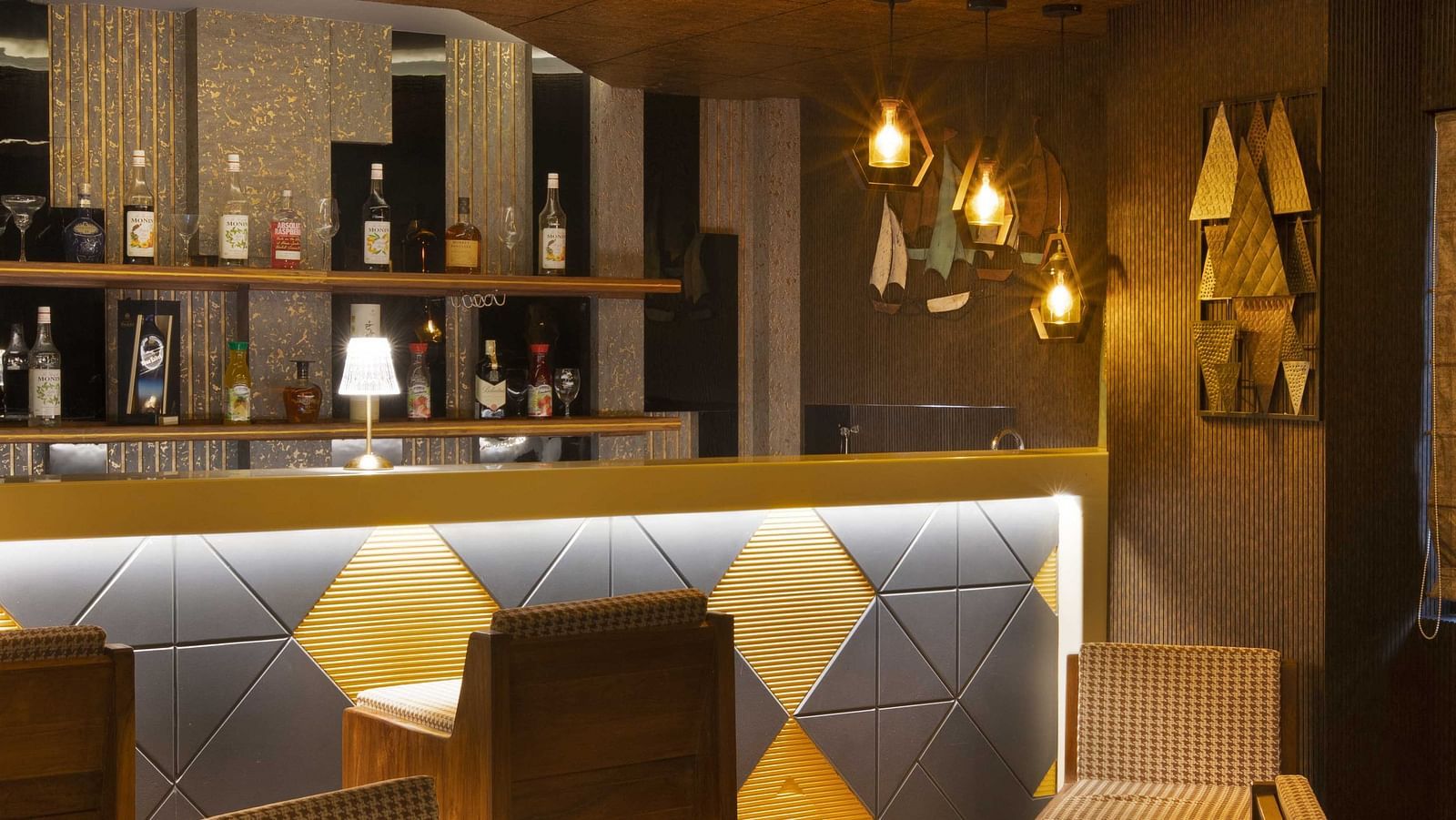 Image of tables and chairs arranged under warm lighting closer to the bar counter at Coral Reef Hotel & Spa in Port Blair