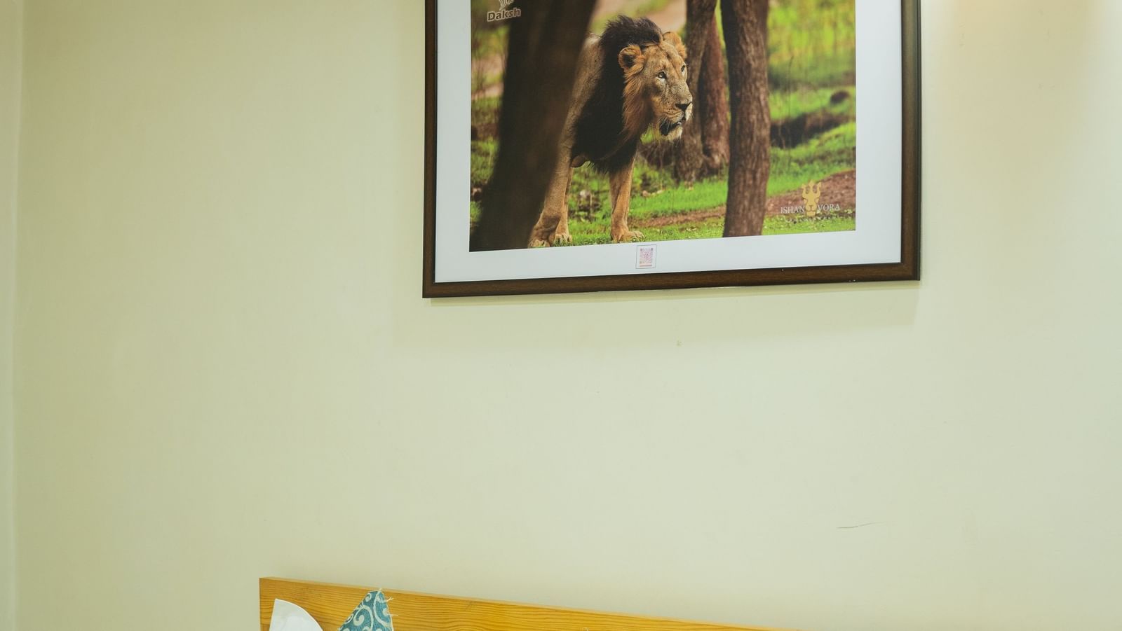 A room with a double bed, blue cushions, framed painting, and aaside table at Daksh Resort & Amusement Park.