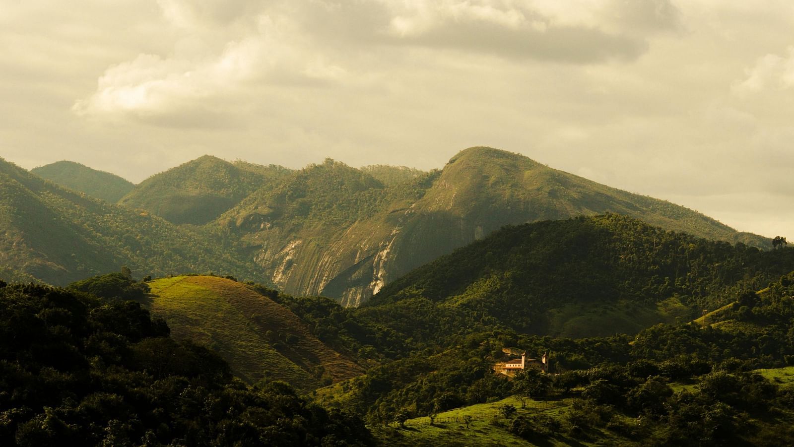 Rolling hills with a golden sunset casting a warm glow over the landscape.
