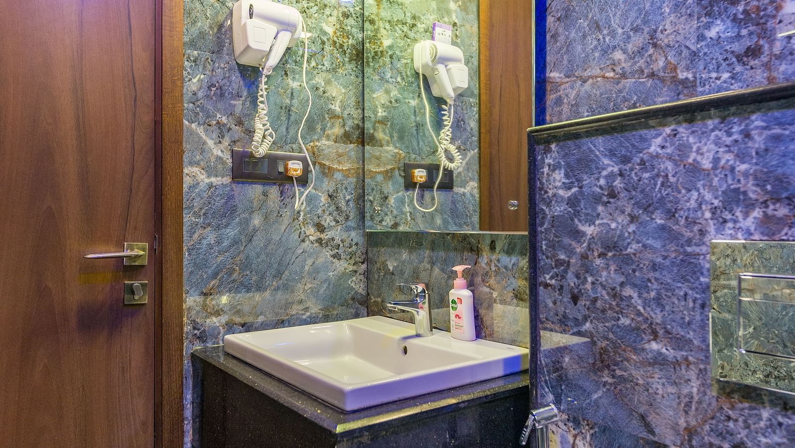 Image of a washroom with a sink and a mirror above it at Hotel Altitude, Madikeri.