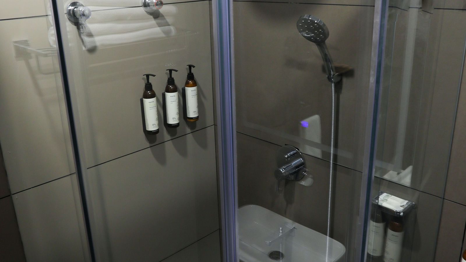 Glass-enclosed shower area with mounted toiletries at Hotel Kyzen HiTech City – Your Zenly Stay.