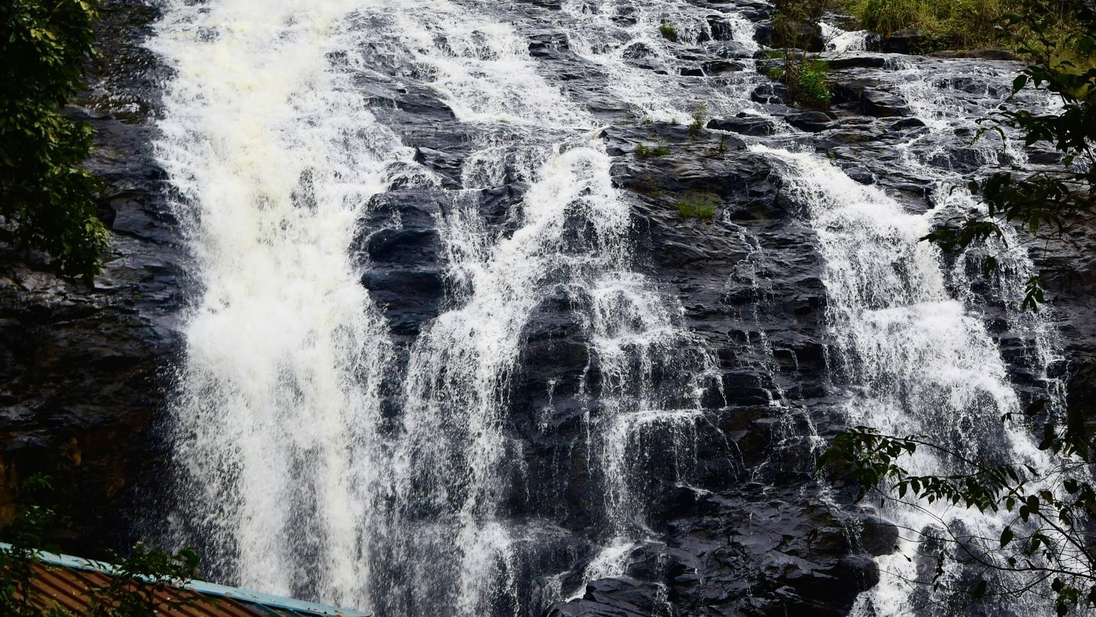 Waterfall flowing through rocks surrounded by lush forest.