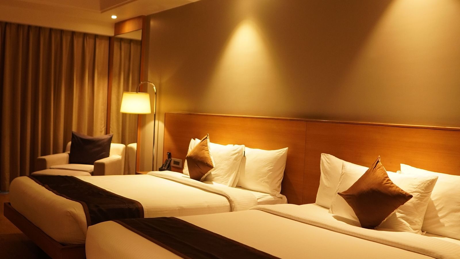 Two spacious beds with warm lighting and neatly made sheets
