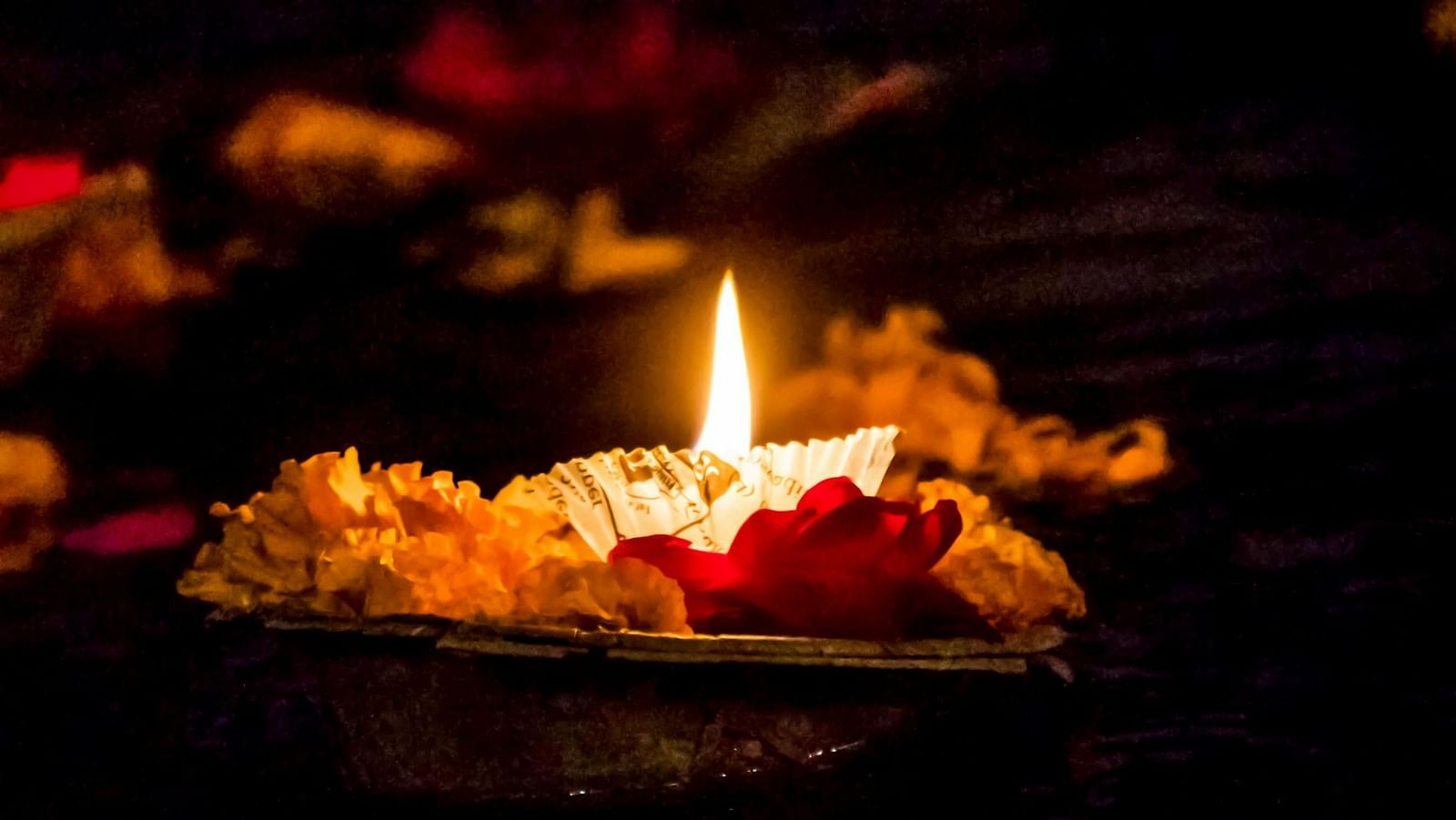 a lit diya on a handmade device floating on a waterbody