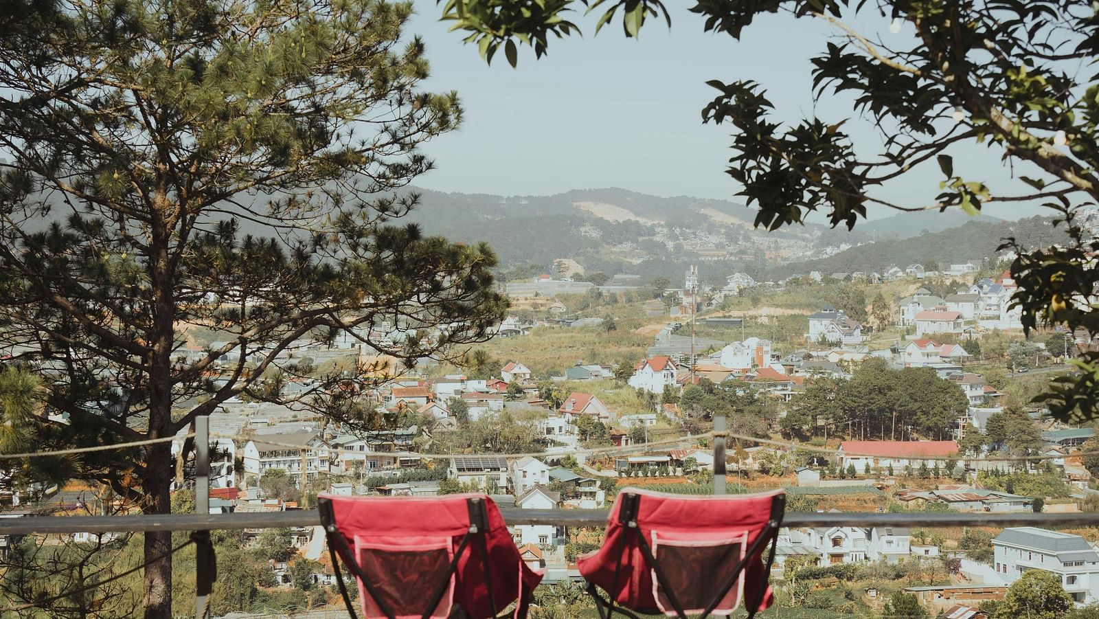 An outdoor seating area with two red chairs overlooking a scenic view.