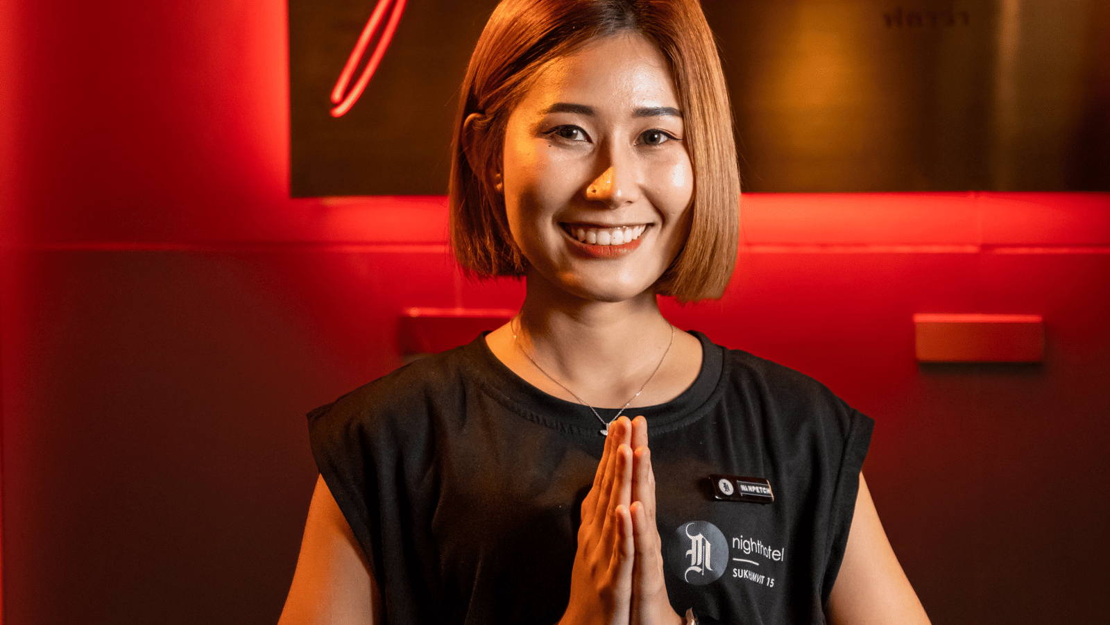 A staff member posing for a picture in front of Flava Lite signage - Night Hotel Bangkok.